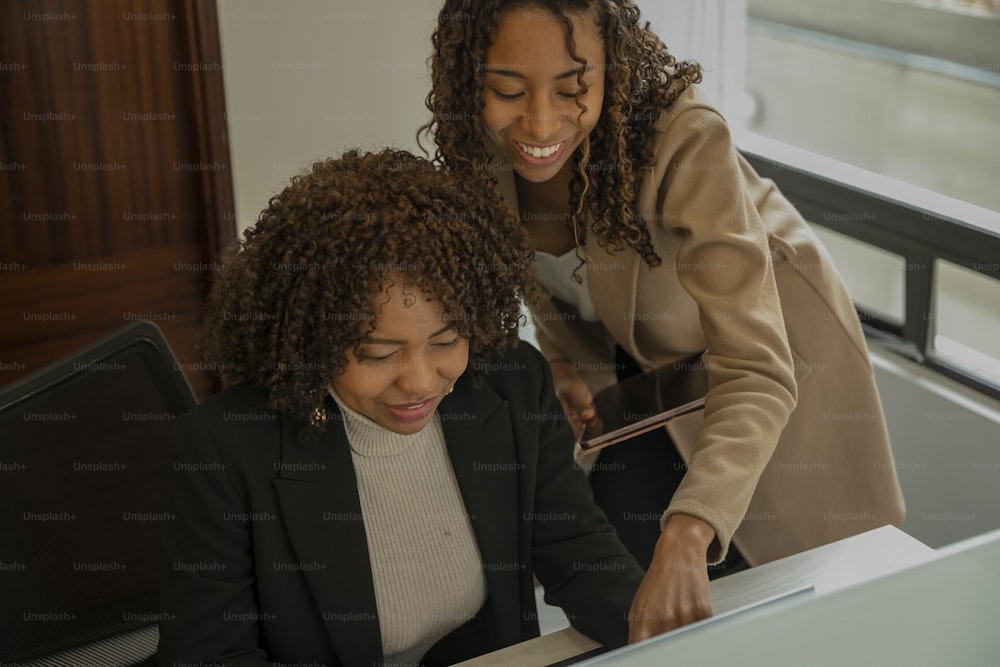 two women sitting at a table working on a laptop