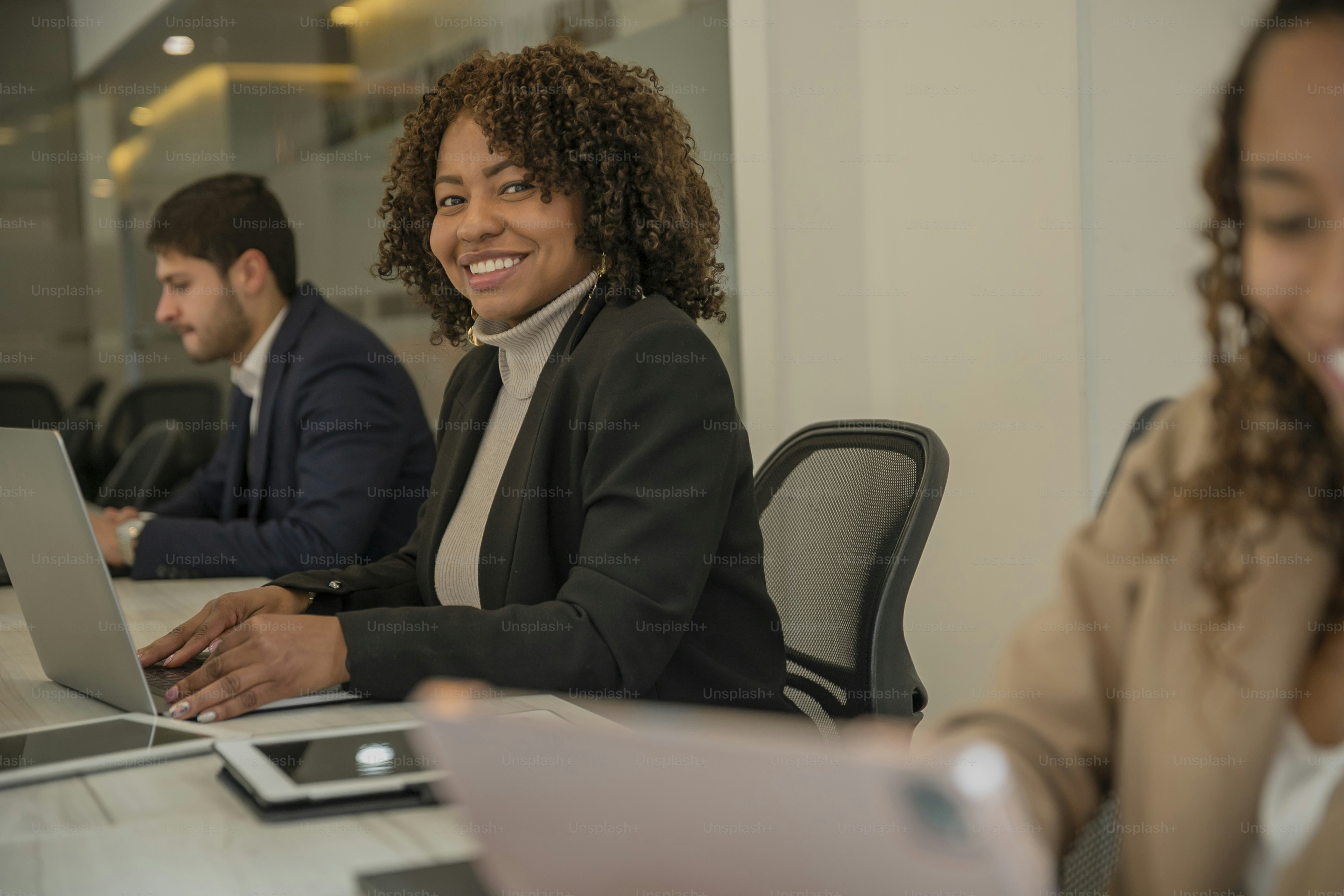 a group of people sitting at a table with laptops