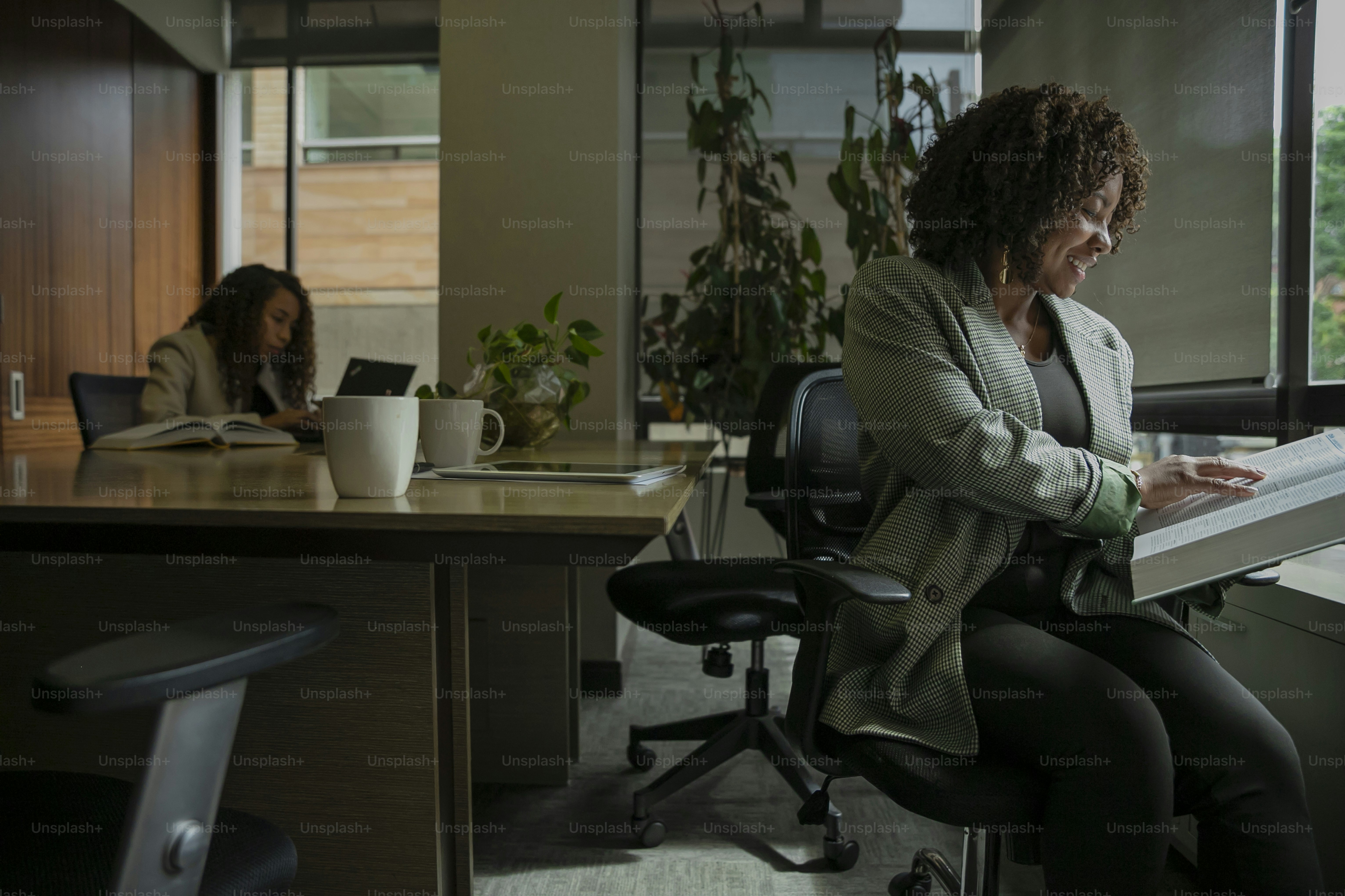 A woman sitting in an office chair reading a book photo Indoors Image