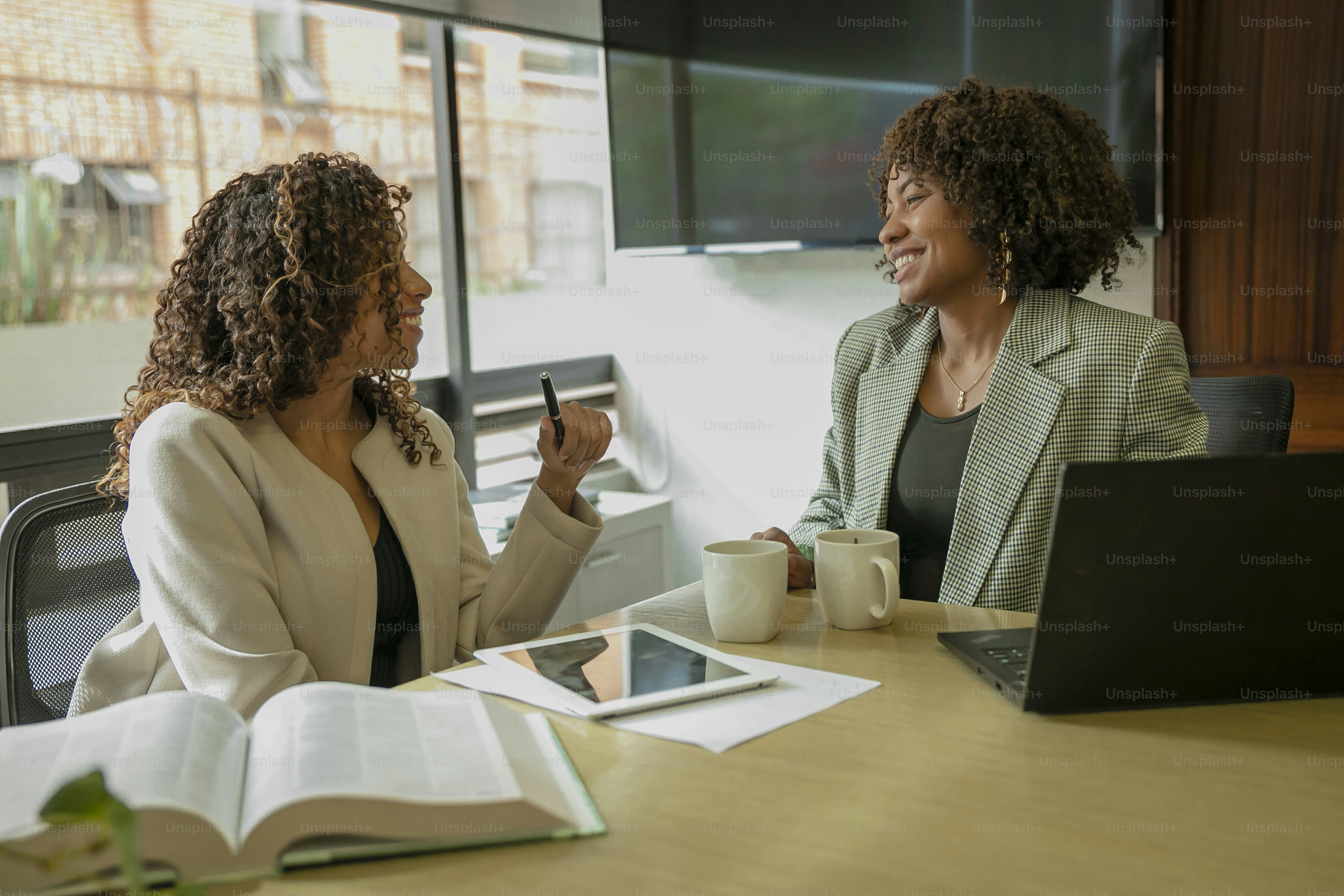 deux femmes assises à une table ayant une conversation