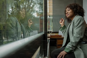 a woman sitting on a window sill smoking a cigarette