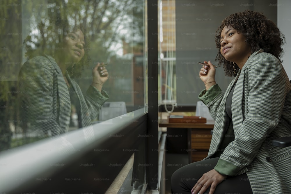 una mujer sentada en el alféizar de una ventana fumando un cigarrillo