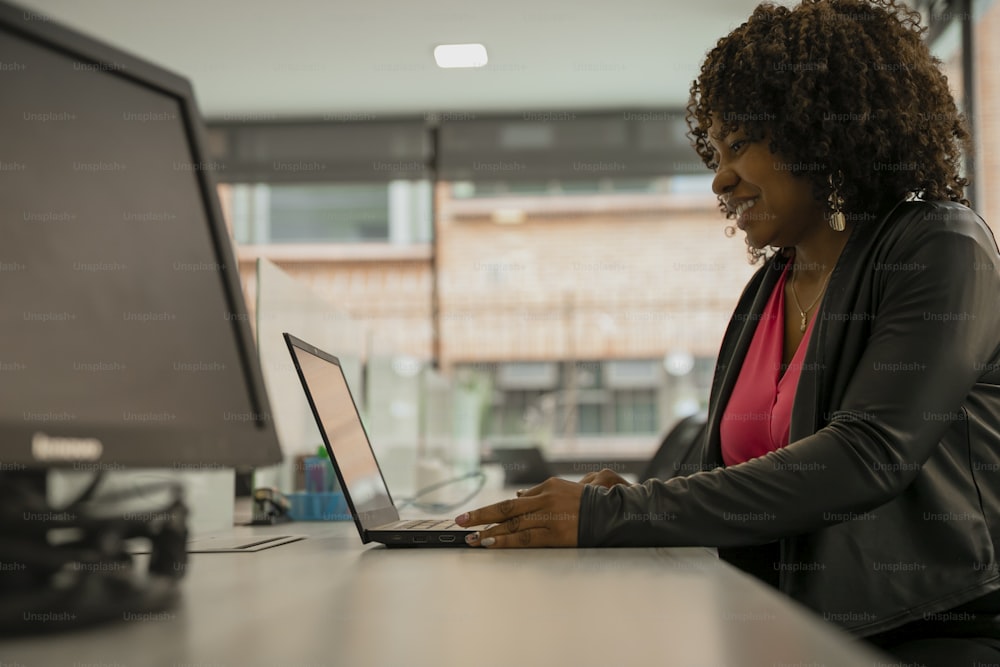 una mujer sentada en un escritorio usando una computadora portátil