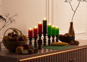 una mesa cubierta con velas y frutas junto a un jarrón lleno de flores