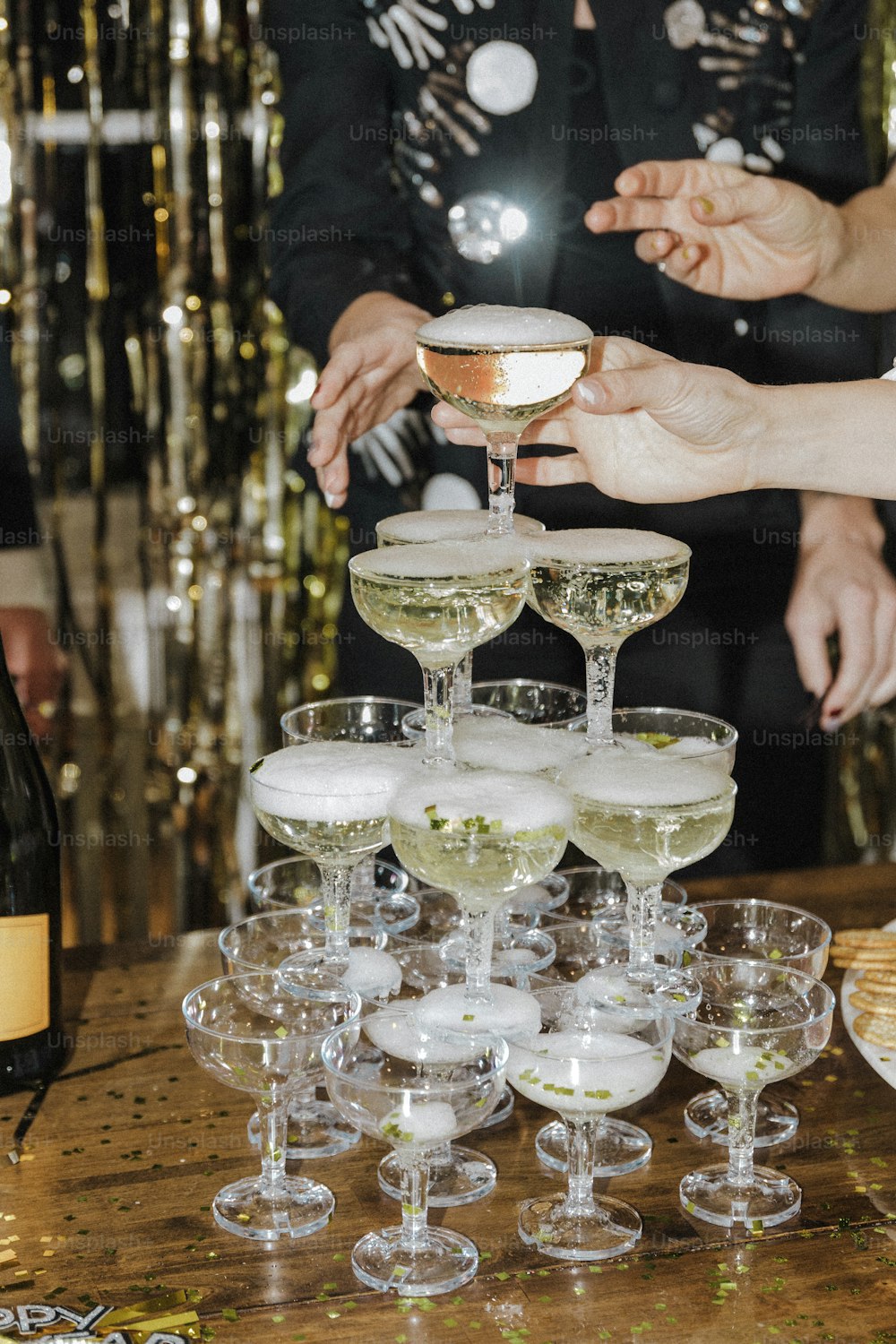 un gruppo di persone in piedi intorno a un tavolo pieno di bicchieri di vino