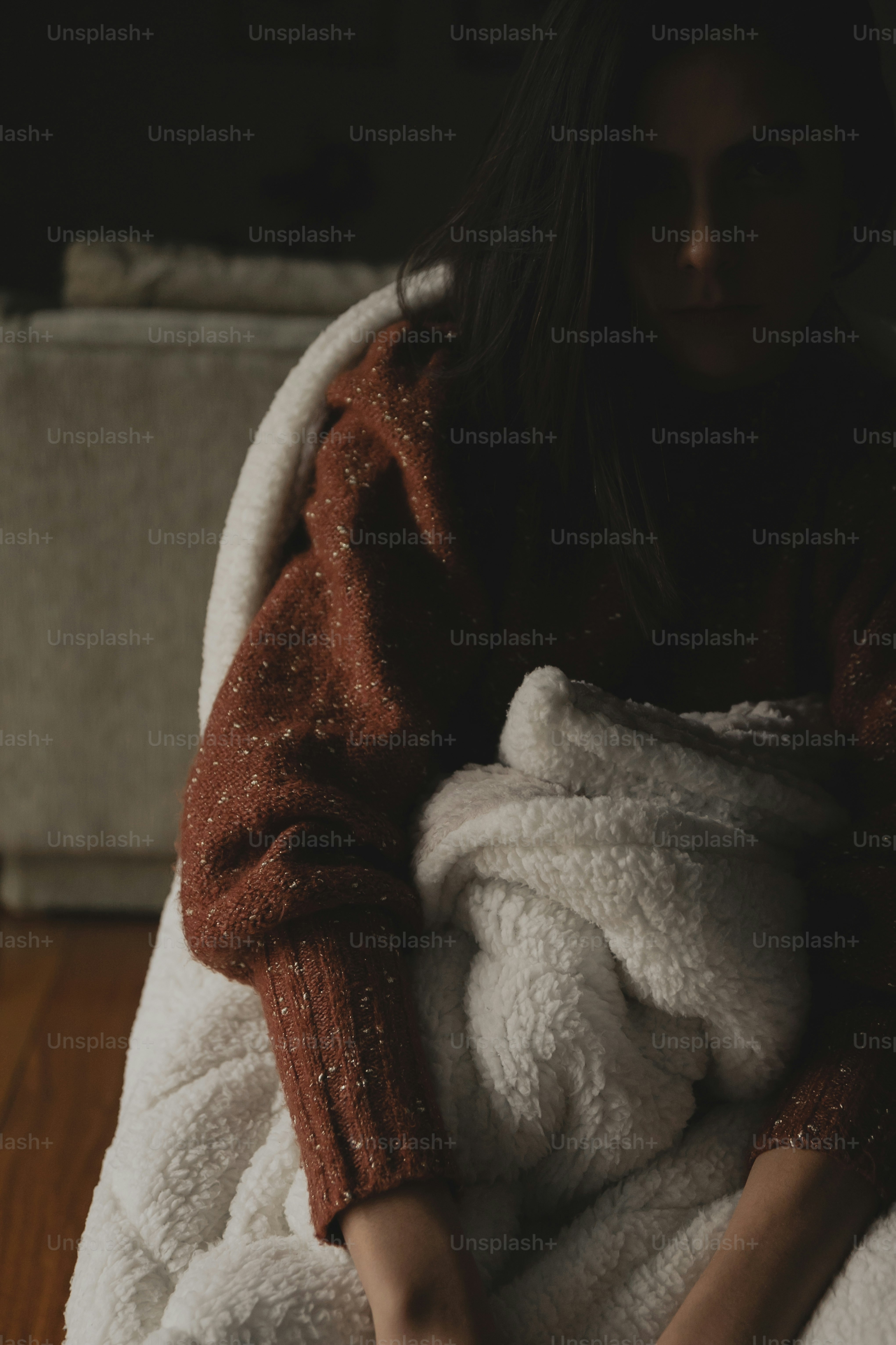 a woman wrapped in a blanket sitting on a couch