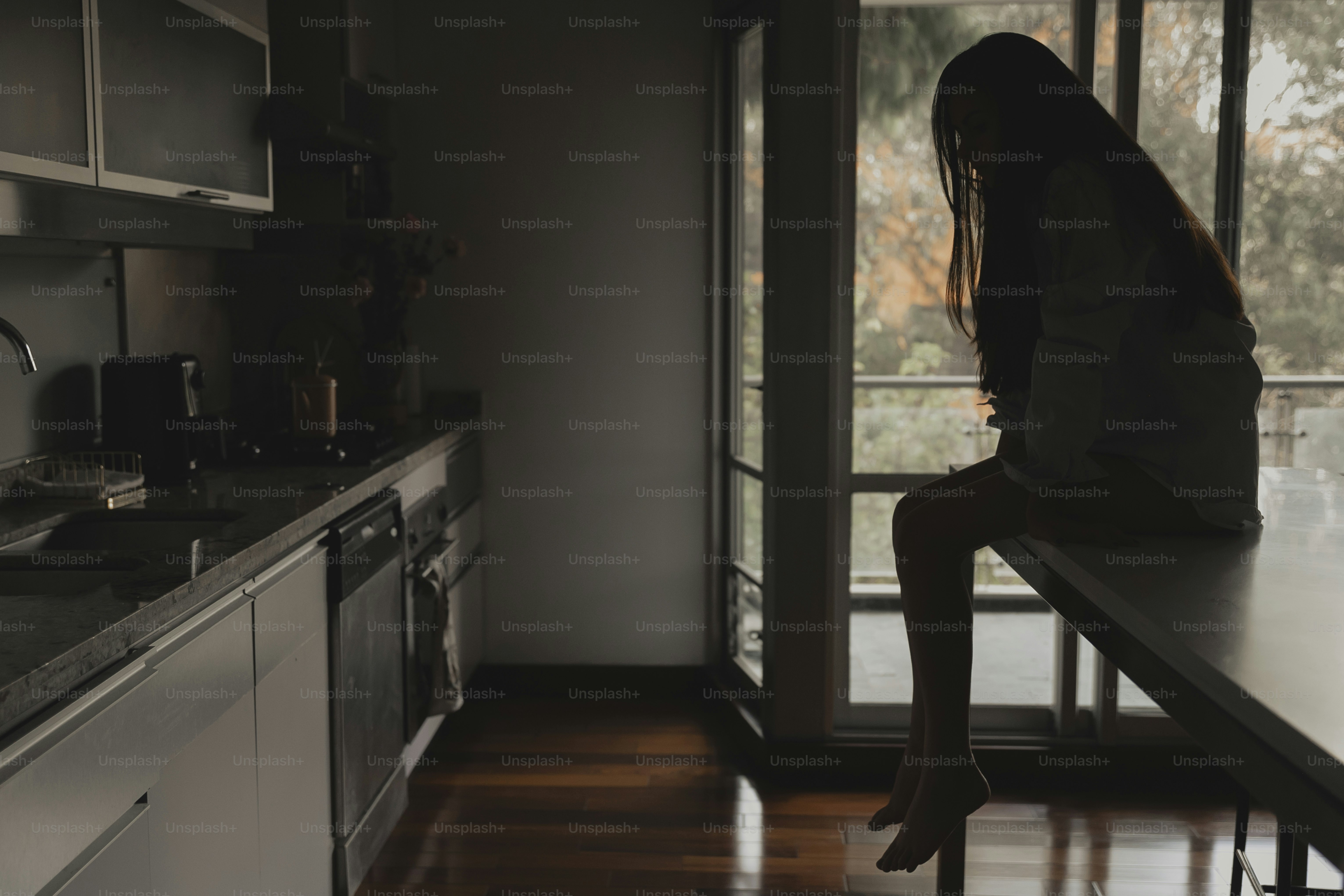 a woman sitting on a counter in a kitchen