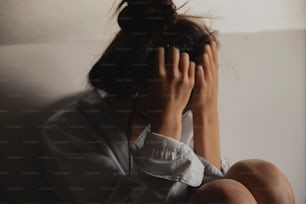 a woman sitting on a couch covering her face with her hands