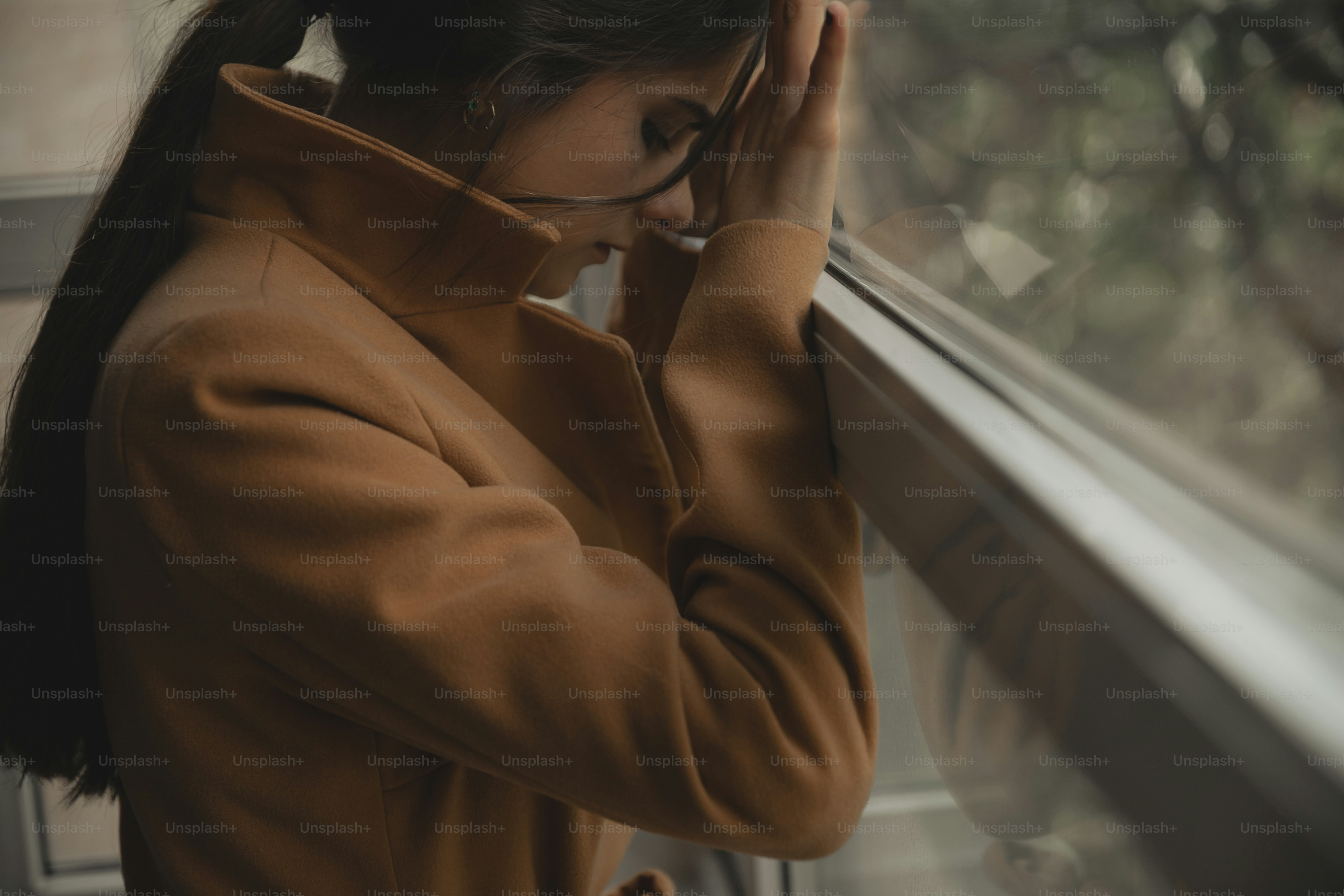 a woman looking out a window with her hand on her head