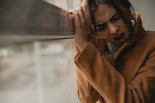 a woman holding her head while looking out a window