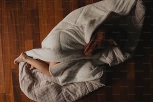 a woman wrapped in a blanket on a wooden floor