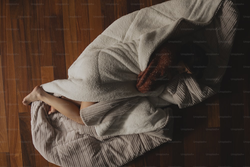 a woman wrapped in a blanket on a wooden floor