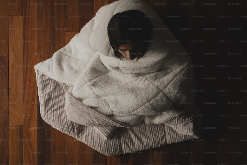a person wrapped in a blanket on a wooden floor