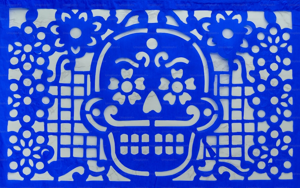 ein blauer Scherenschnitt eines Totenkopfes mit Blumen