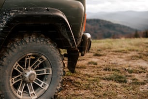 Um jipe estacionado em um campo com montanhas ao fundo