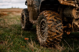 a muddy four wheeler parked in a grassy field