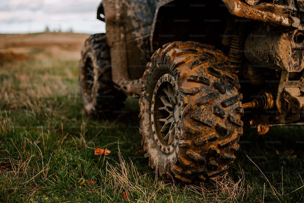 a muddy four wheeler parked in a grassy field