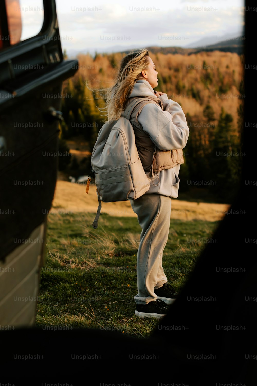 a woman standing in a field with a backpack