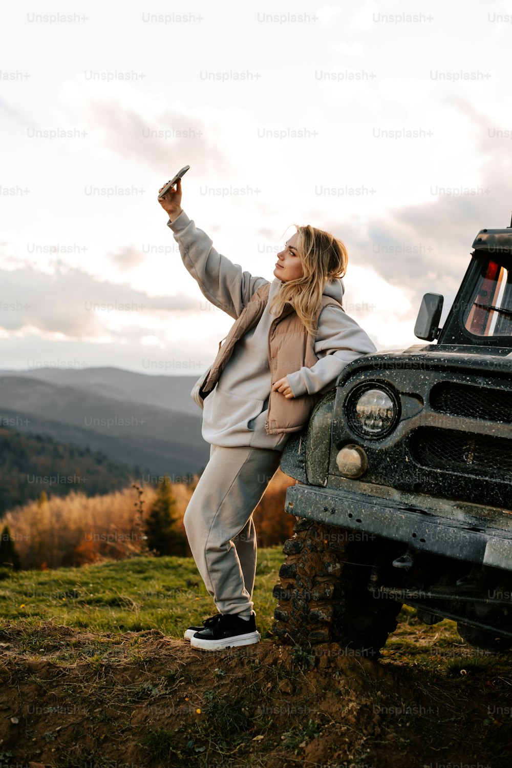 Une femme appuyée sur le capot d’une jeep