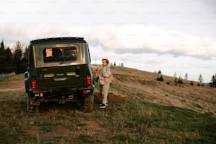 a man standing next to a vehicle on a hill