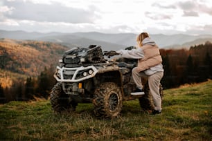 a woman sitting on a four - wheeler in the mountains