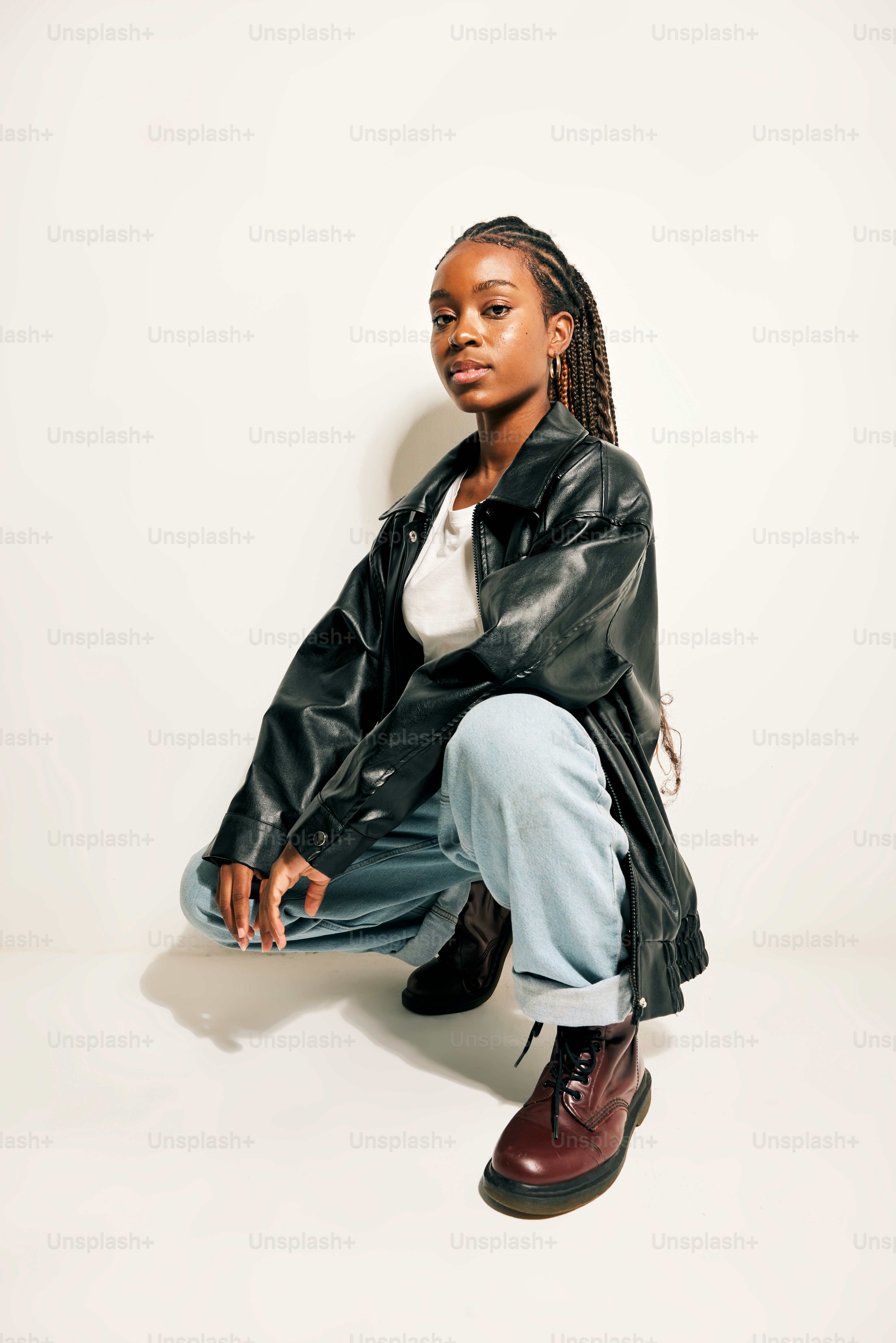 A woman sitting on the ground wearing a black jacket and jeans photo ...