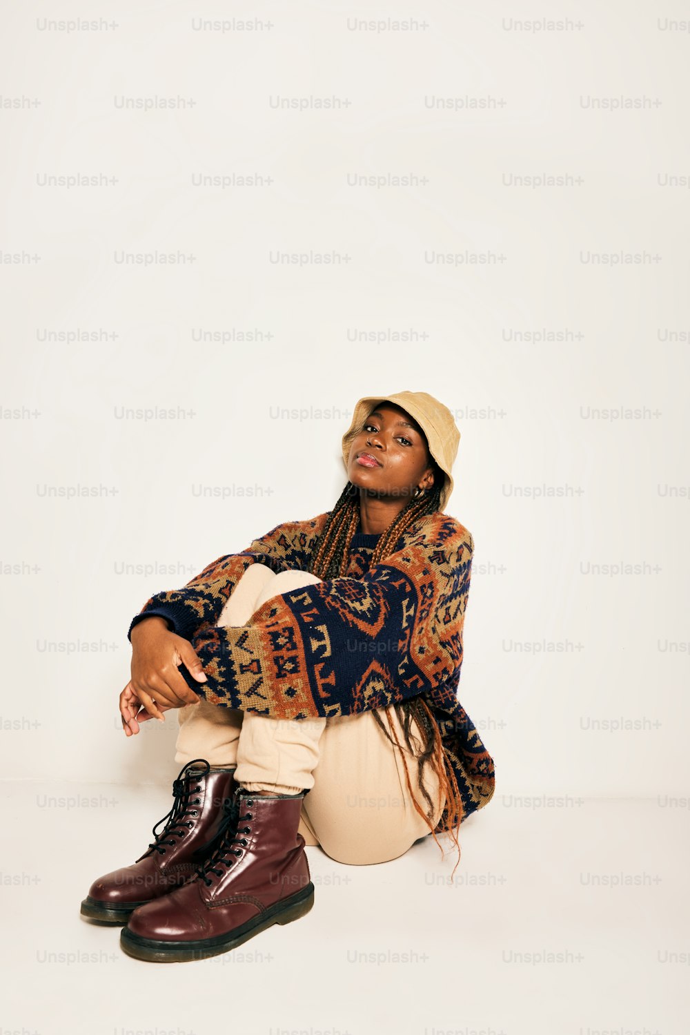 a woman sitting on the ground wearing a hat and boots