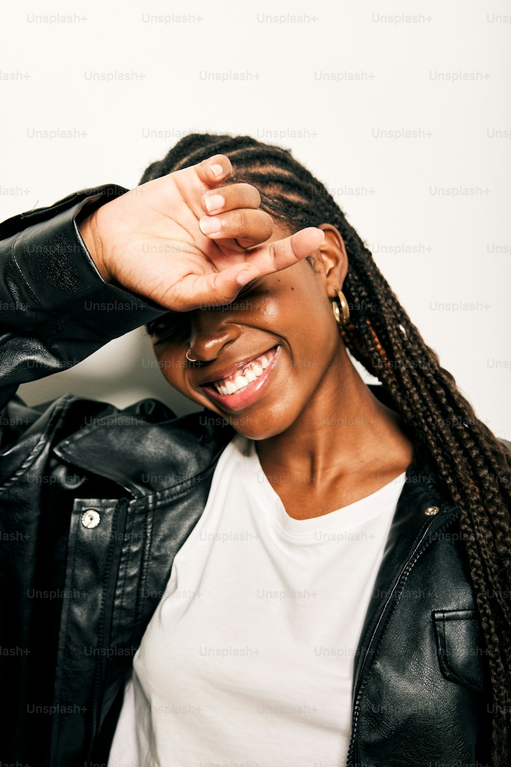 a woman in a leather jacket smiling and covering her eyes