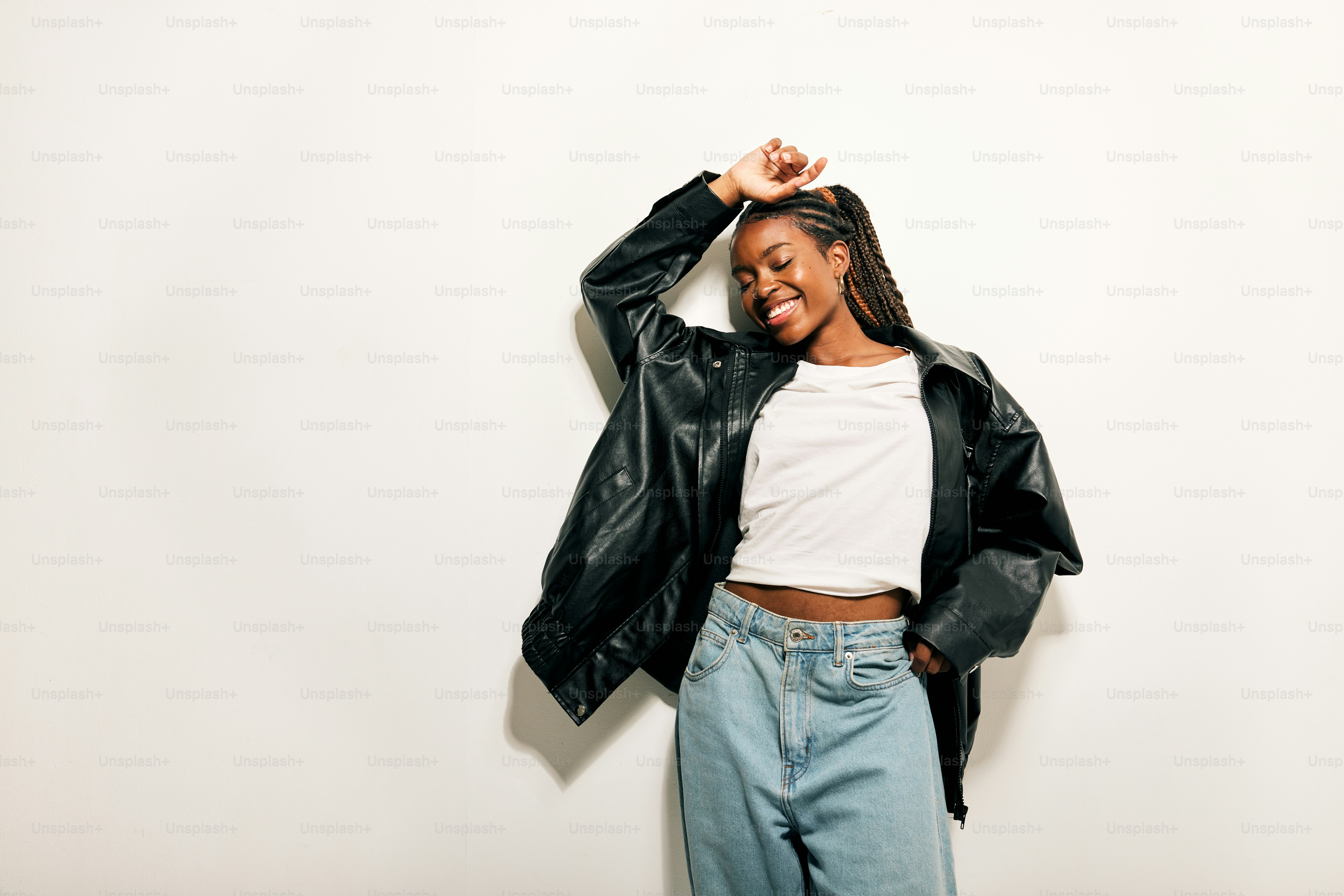 Una mujer con chaqueta negra y jeans posando para una foto