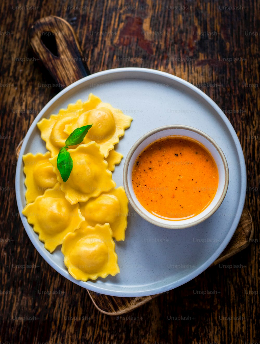 a plate of ravioli and sauce on a wooden table