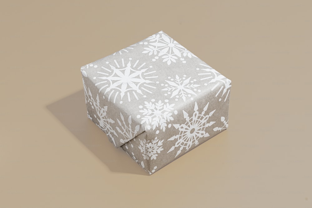 un cadeau enveloppé dans du papier blanc avec des flocons de neige dessus