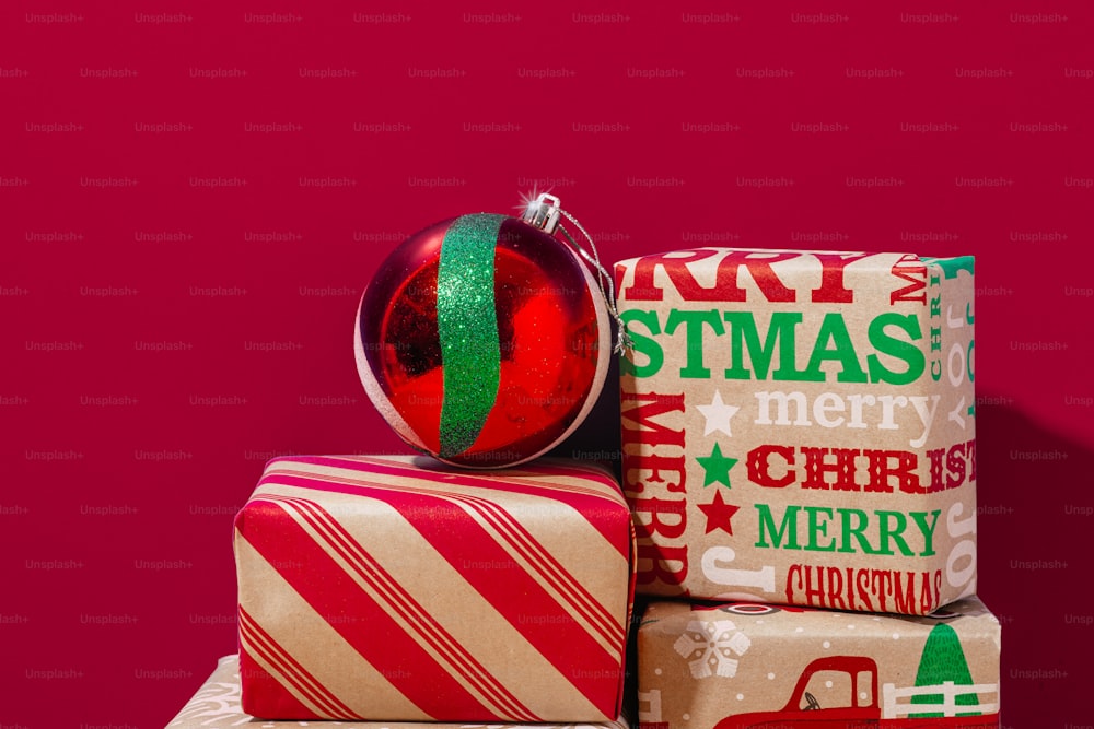 a stack of wrapped presents with a christmas ornament on top