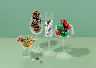 three wine glasses filled with candy and pine cones