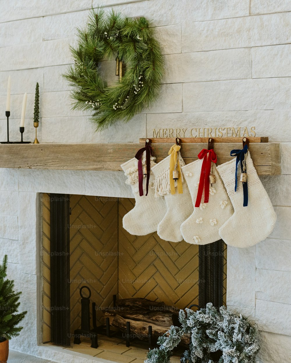 stockings hanging from a fireplace with a merry christmas sign