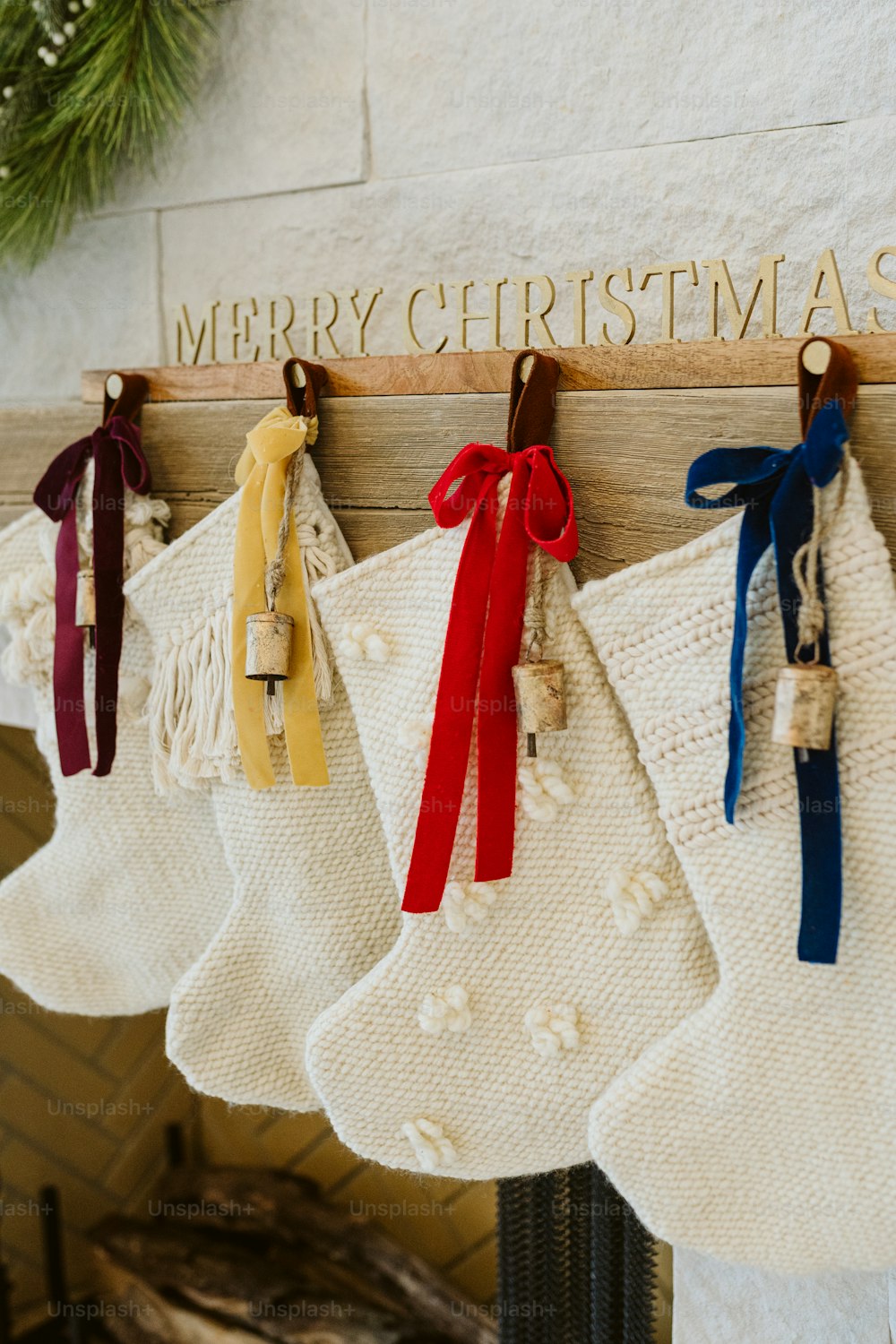 stockings hanging from a fireplace with a merry christmas sign in the background