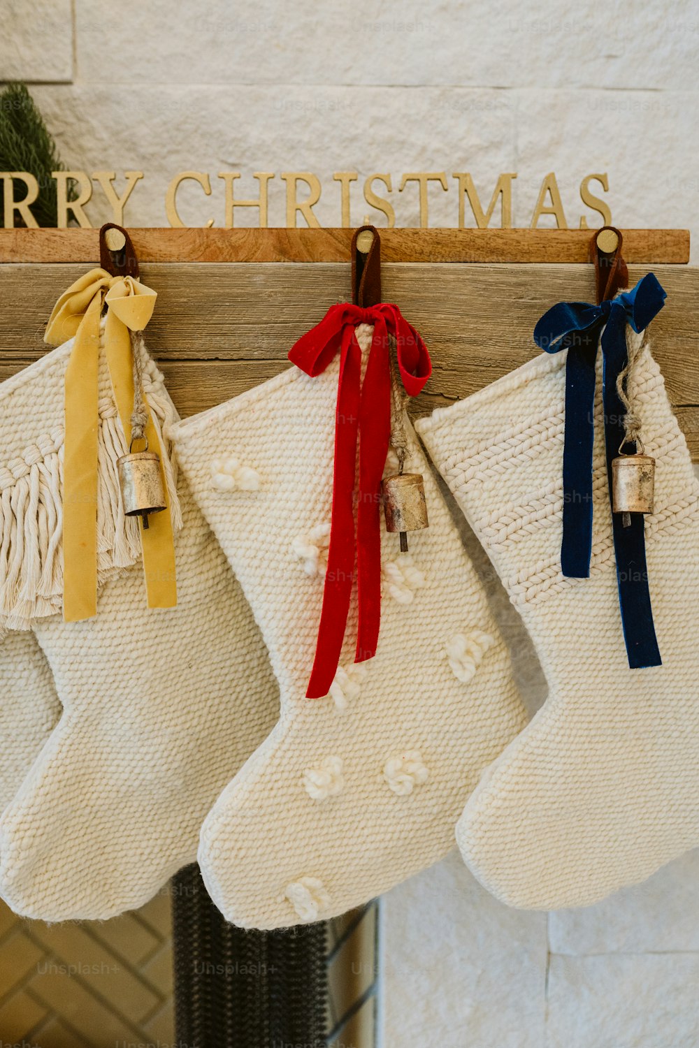 Três meias penduradas em uma lareira com uma placa de Feliz Natal acima delas