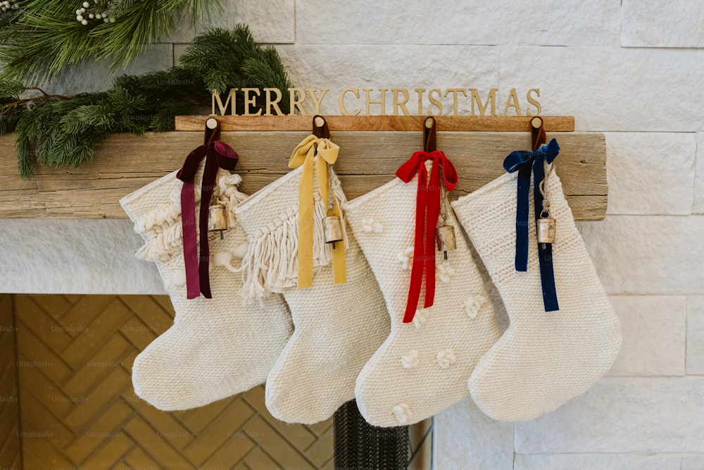 stockings hanging from a mantel with a merry christmas sign