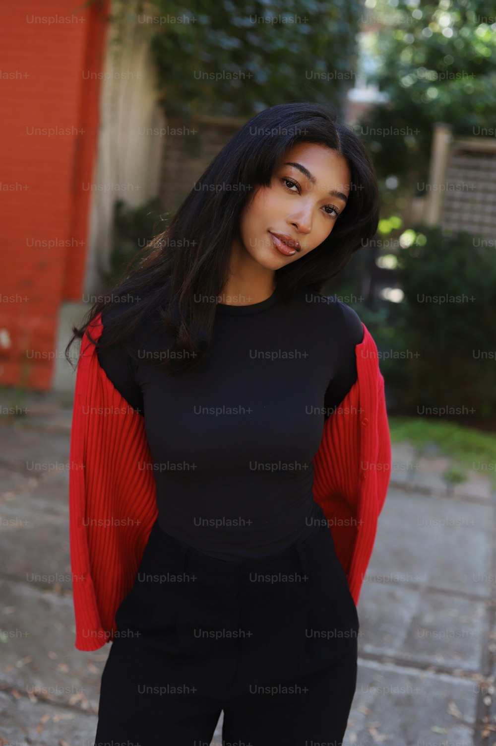 a woman standing on a sidewalk wearing a black and red top