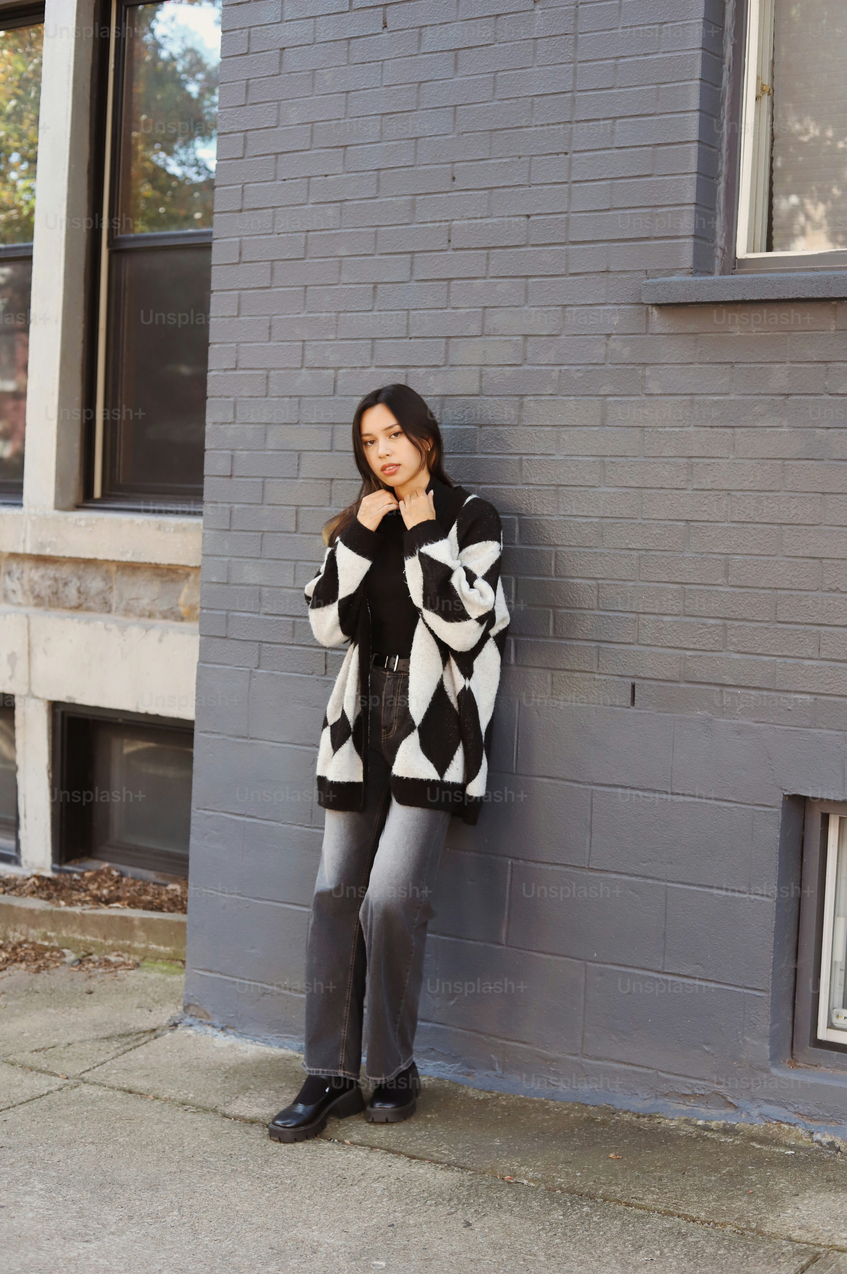 a woman leaning against a brick wall posing for a picture