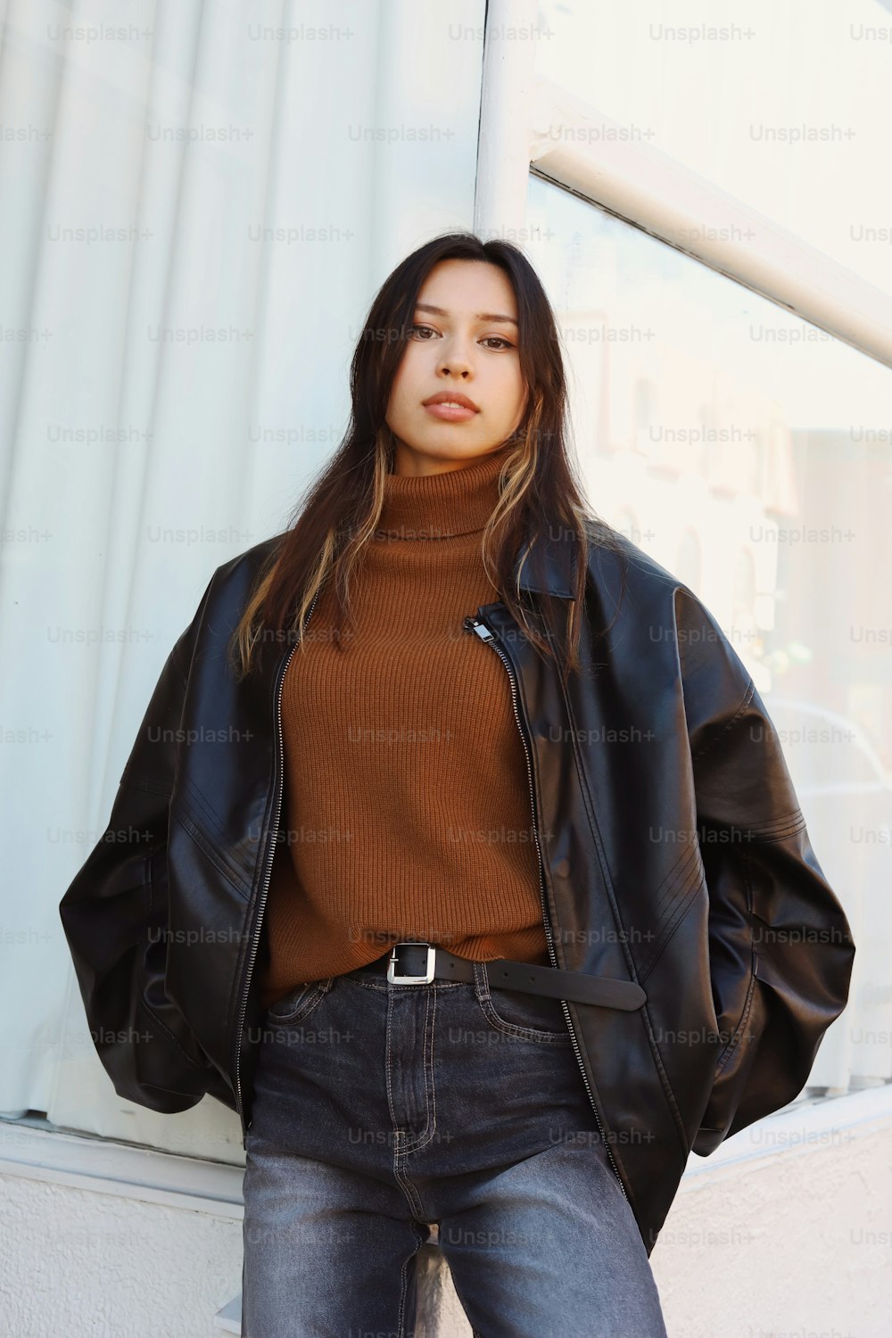 a woman wearing a brown turtle neck sweater and black leather jacket