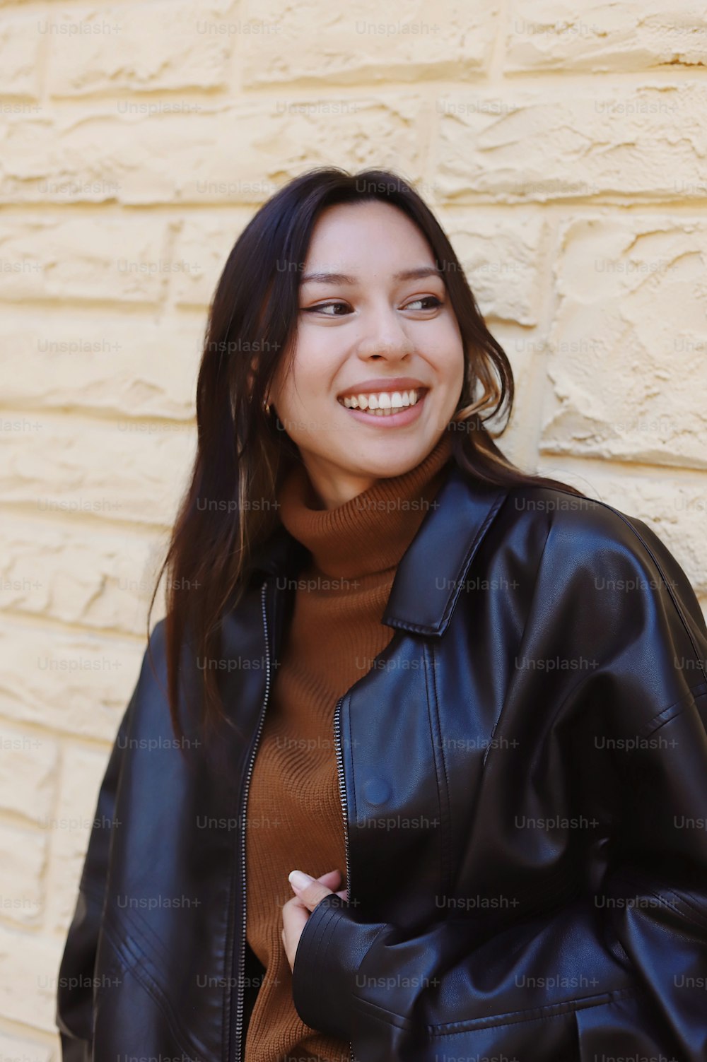 a woman in a brown turtle neck sweater and a black leather jacket