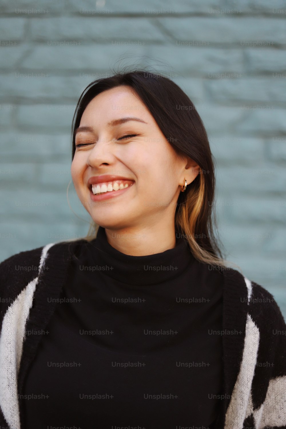 a woman smiling and wearing a black and white sweater