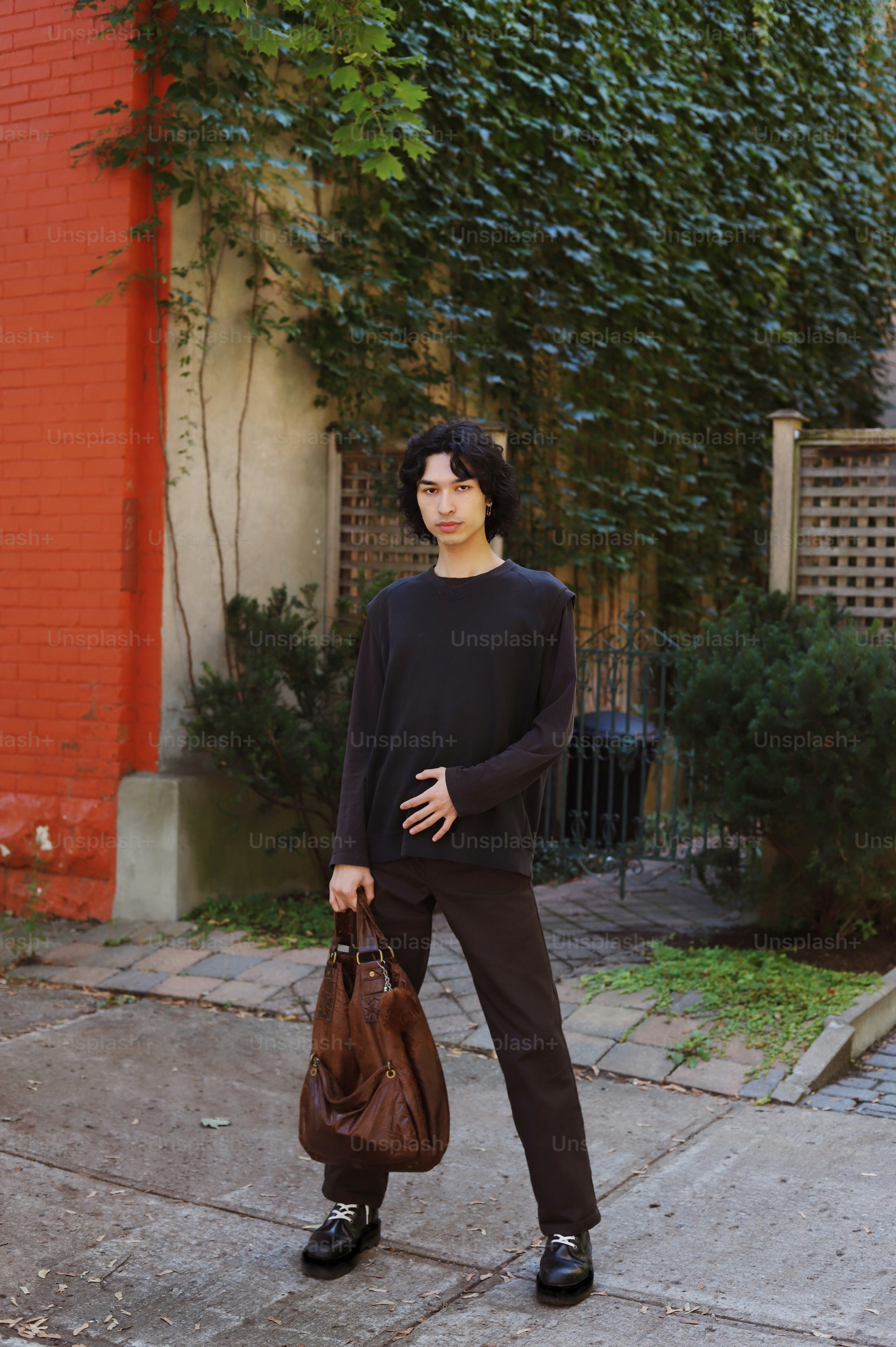 a woman standing on a sidewalk holding a brown bag
