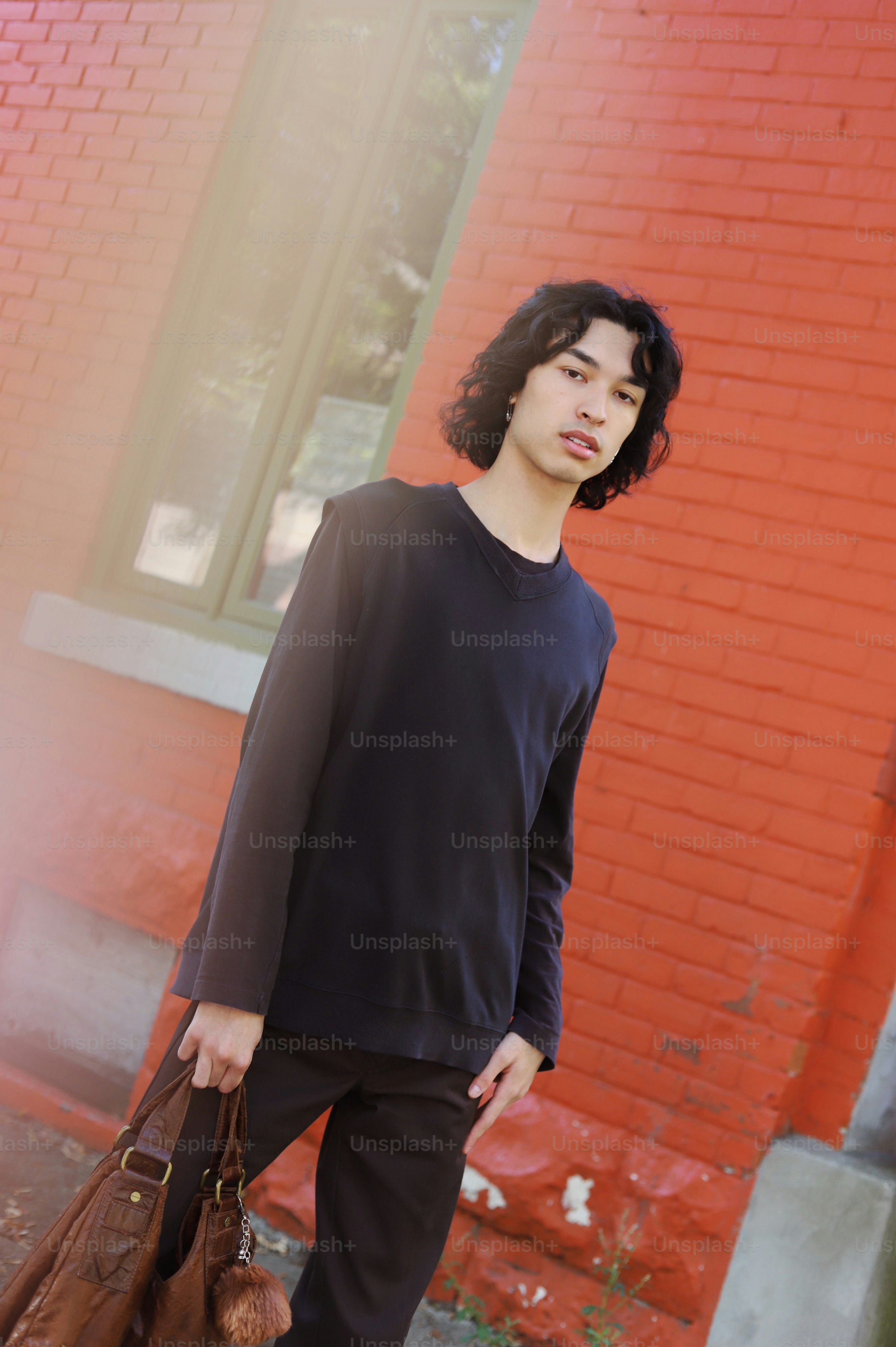 A young man standing in front of a red brick building photo – Autumn ...