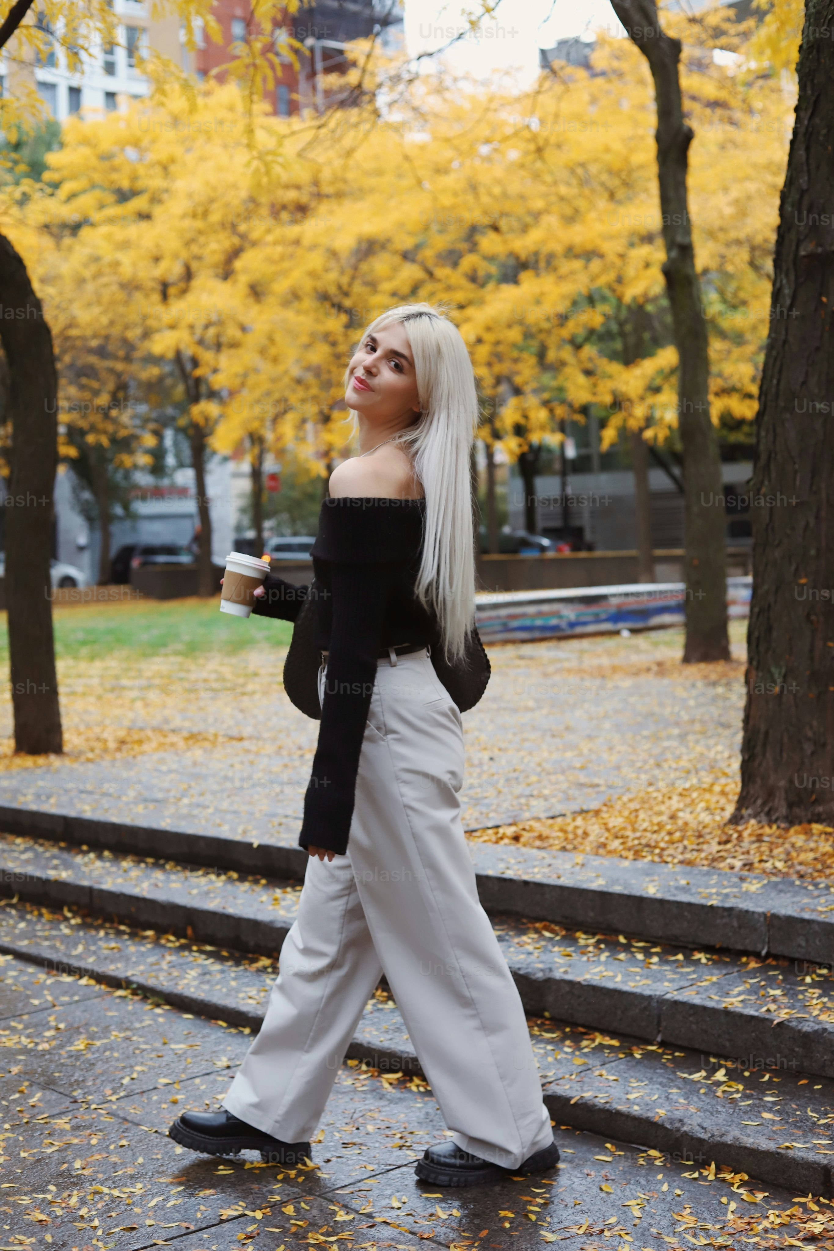 a woman walking down a street with a cup of coffee