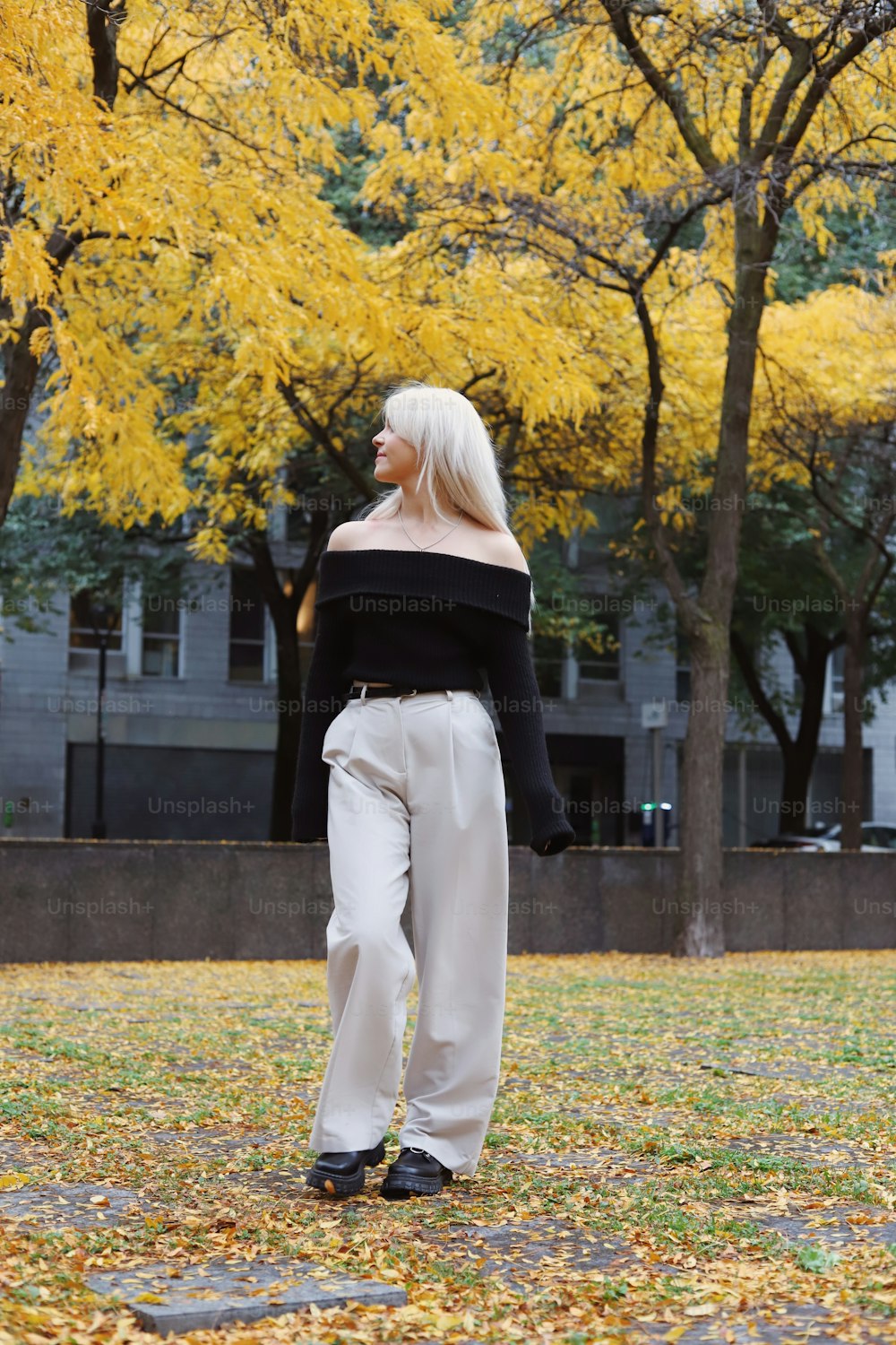 a woman in a black off the shoulder top is standing in a park