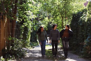 three people walking down a path in the woods
