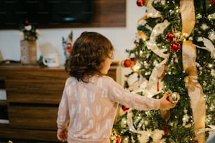 a little girl standing next to a christmas tree