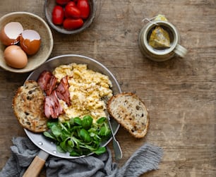 a bowl of eggs, bread, and vegetables on a table