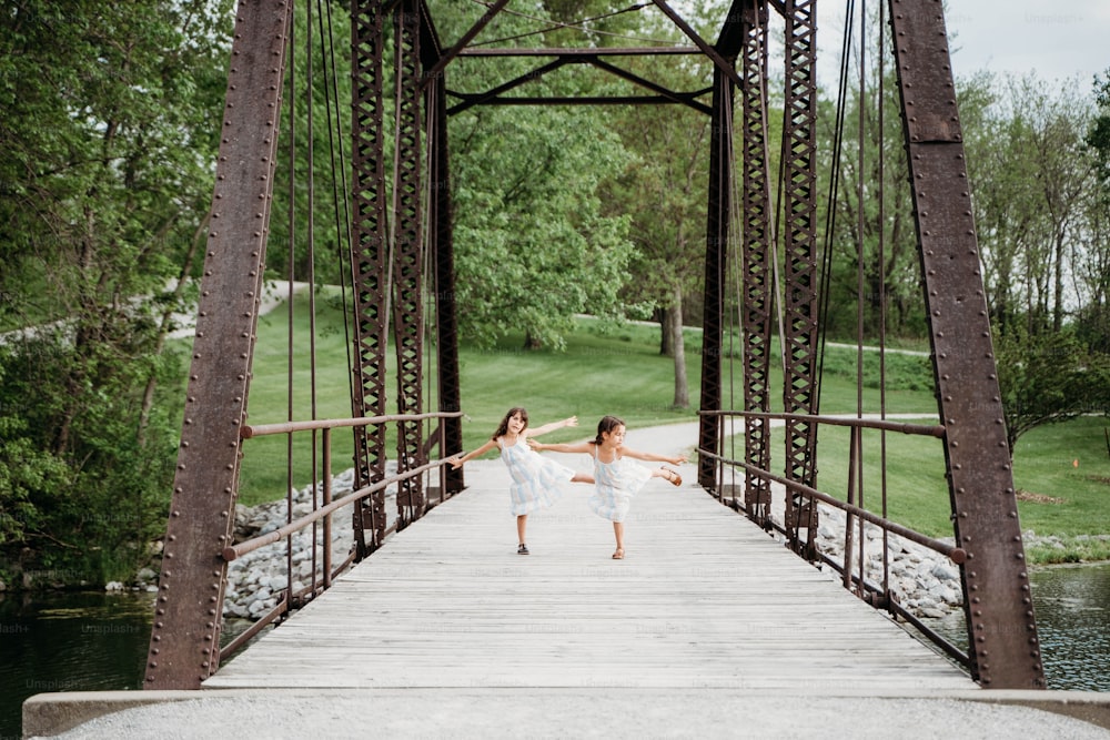 two young girls are dancing on a bridge